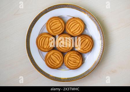 Tasty wheat biscuits filled with milk cream served on a white plate on wooden background. Top view Stock Photo