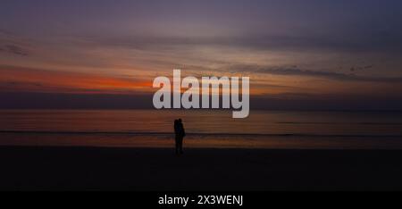 Silhouette Dark mother holding baby on the beach with Sunset Nature Coast Landscape Summer Stock Photo