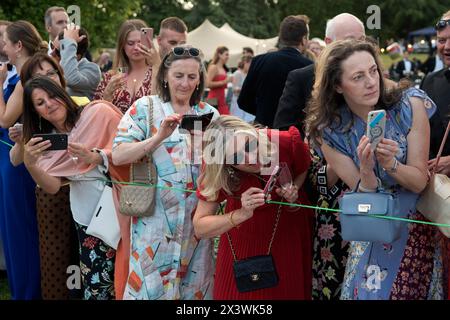 Wealthy rich women using smartphones UK 2020s. Hurlingham Club is an exclusive private social club in the Fulham area of London. The annual summer garden party - Fête Champête, where members show off their classic and vintage cars in the Concourse d'Elégance; the cars are driven around the club grounds.  Ladies wait to snap the classic cars with their iphones. London, England 11th June 2022 UK 2020s HOMER SYKES Stock Photo