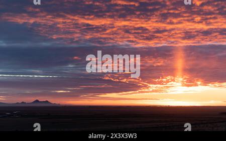 A beautiful sunset with a long rainbow in the sky. The sky is filled with clouds and the sun is setting Stock Photo