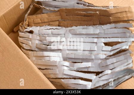Cardboard box full of cut packaging paper material for parcel protection. Stock Photo