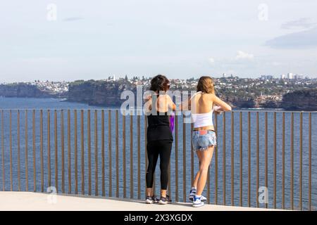 Burragula lookout on the Fairfax walking track at North Head Manly, two females enjoy the view across Sydney Harbour to South heads, NSW,Australia Stock Photo