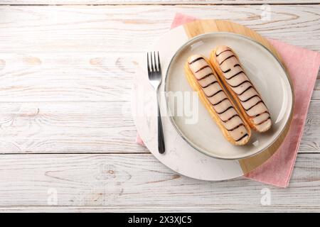 Tasty glazed eclairs served on wooden rustic table, top view. Space for text Stock Photo