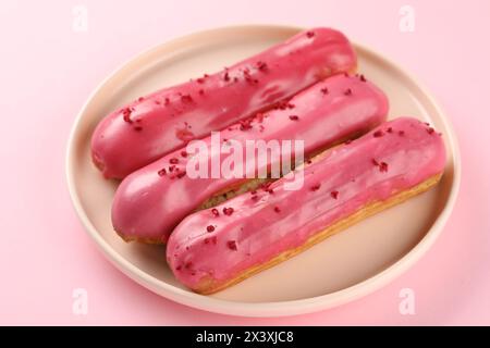 Delicious eclairs covered with glaze on pink background Stock Photo