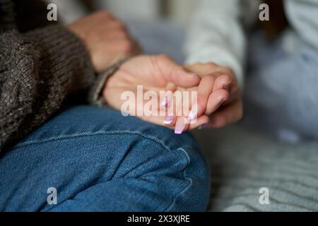 Close Up Of Mother Holding Hands With Teenage Daughter With False Nails Providing Love, Support And Advice Stock Photo