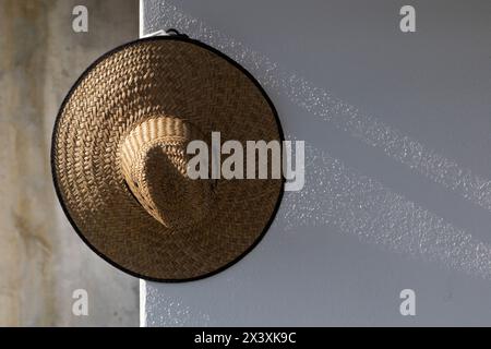 straw hat hanging on the wall, natural soft sunset light Stock Photo