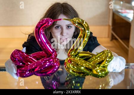 London, UK.  29 April 2024. A staff member with two works from the six 'Balloon Animals Collector's Set', 2017-2019, by Jeff Koons, (Est. £50,000 - £70,000), at the preview of ‘Hot Off The Press’, a sale of prints and new editions, created and published within the last fifty years, by well-known contemporary artists.  The works will be auctioned at Bonhams New Bond Street on 1 May. Credit: Stephen Chung / Alamy Live News Stock Photo