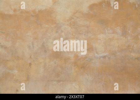 Old rough yellow ochre colored cracked painted plaster wall texture. Shabby earth coloured grunge texture, building facade. Closeup of historical Stock Photo