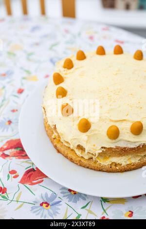 Homemade orange cake for Easter, topped with orange mini eggs, on a floral tablecloth Stock Photo