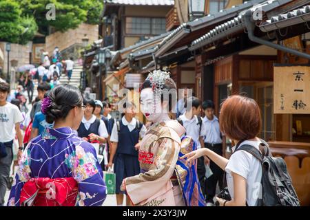 Kyoto, Japan - 15 June 2016: Woman in Geisha costume and makeup amongst the tourists on the ancient streets of Kyoto. Famous as an area for Geishas. Stock Photo