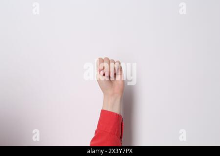 SOS gesture. Woman showing signal for help behind her back on grey ...