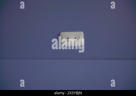 Old electric plug on blue wall. Stock Photo