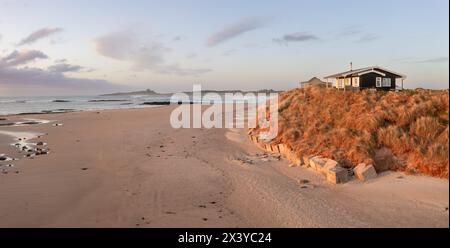 A remote beach hut with a sea view on the Northumbrian sand dunes over looking Embleton Bay and Dunstanburgh Castle at sunset Stock Photo