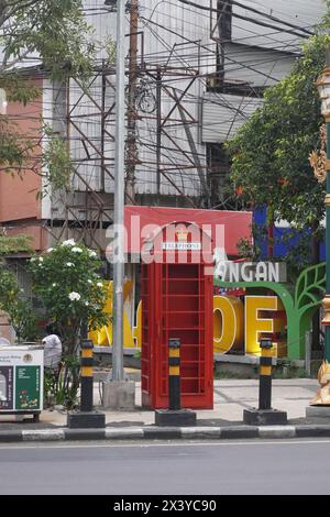 The red telephone box is on the side of the road as decoration in Kayutangan Heritage, Malang Stock Photo