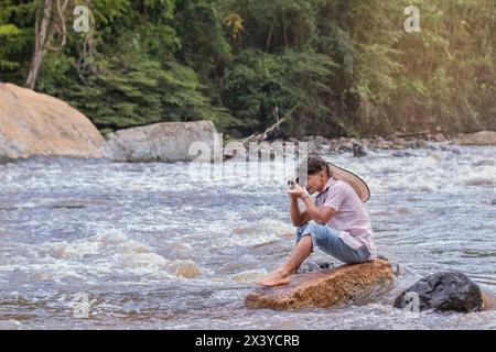 lifestyle. young latino man sitting on a rock taking pictures with an analog camera Stock Photo
