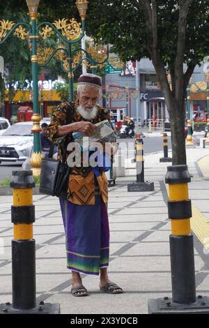 A Muslim grandfather who was standing reading something on the sidewalk Stock Photo