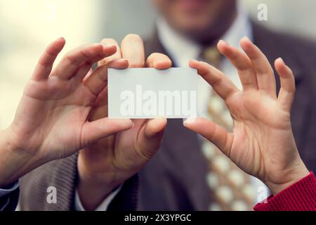 Three person holding a white card in his hand. You can put a text, message or logo on the empty surface. Stock Photo