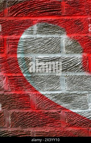 Half of a heart shape spray painted in red and white on a brick wall Stock Photo