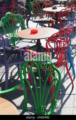 Street cafe with round tables and backrest chairs of different colors in center of Bucharest on sunny day Stock Photo