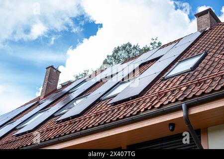 The rooftop solar installation on a family home, set against a backdrop of lush trees and blue skies, showcases a commitment to clean energy and carbo Stock Photo