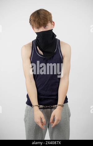 A Teenage Boy Wearing a Mask, Arrested in Handcuffs Stock Photo