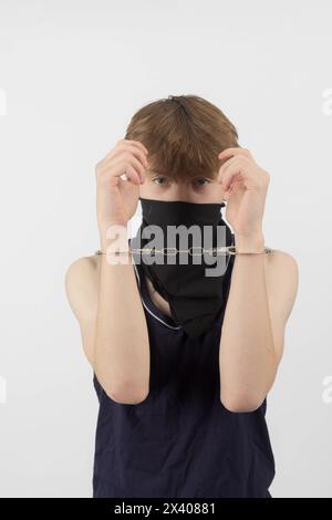 A Teenage Boy Wearing a Mask, Arrested in Handcuffs Stock Photo