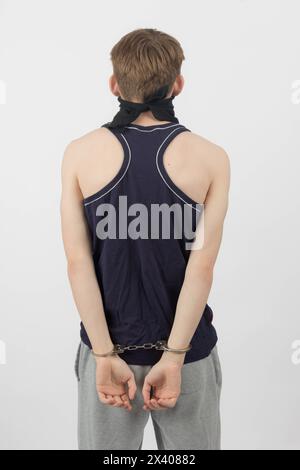 A Teenage Boy Wearing a Mask, Arrested in Handcuffs from Behind Stock Photo