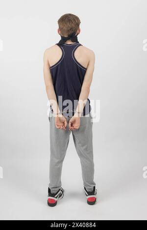 A Teenage Boy Wearing a Mask, Arrested in Handcuffs from Behind Stock Photo