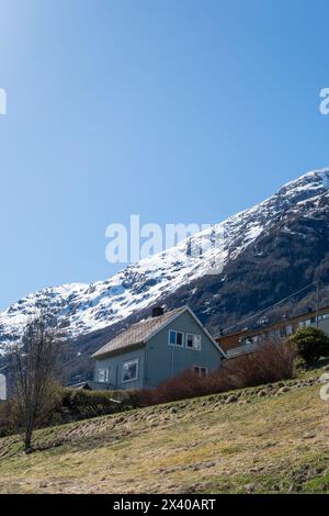 House in Olden, Norway with snow covered mountain tops in the background Stock Photo