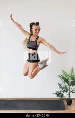 Female athlete jumping joyfully in a fitness studio Stock Photo