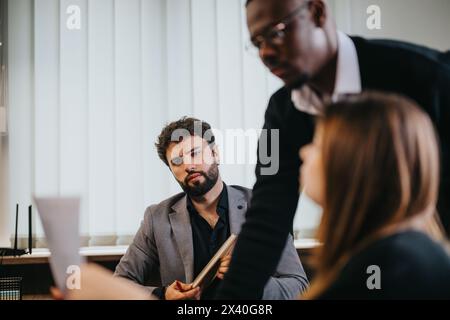 Focused professionals discussing project strategies in modern office setting Stock Photo