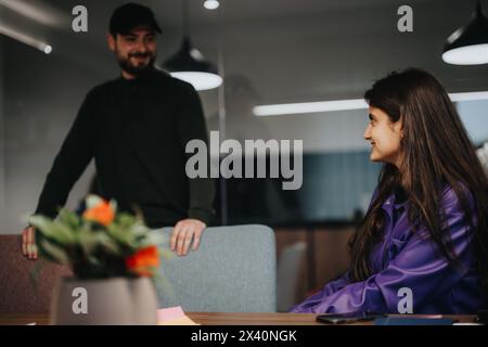 Two business professionals engaging in a casual conversation in a modern office setting Stock Photo