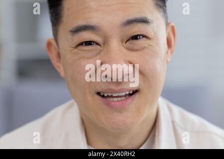 A high-resolution image featuring a close-up portrait of a cheerful middle-aged Asian man. His warm smile and confident eyes convey positivity and approachability. Stock Photo