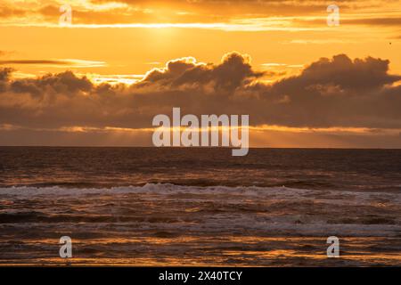 Beautiful sunset with Fingers of God extending down from behind the clouds over the Pacific Ocean from the beach at Cape Disappointment State Park ... Stock Photo