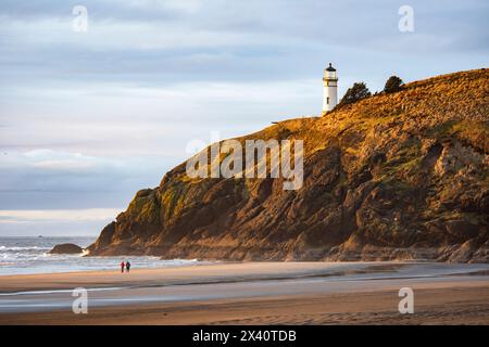 A couple walking on the beach below the North Head Lighthouse at Cape Disappointment State Park near the mouth of the Columbia River, Washington State Stock Photo