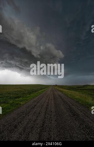 Dramatic clouds associated with a very strong supercell thunderstorm in Kansas. An old gravel road is here as the storm passes overhead Stock Photo