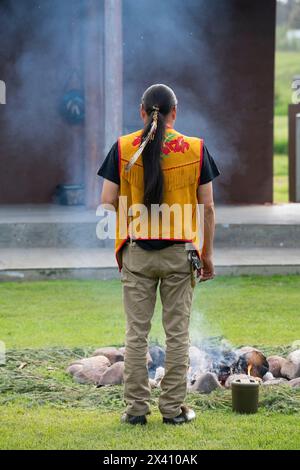 Indigenous man stands in front of a fire during a drum dance; Fort Simpson, Northwest Territories, Canada Stock Photo