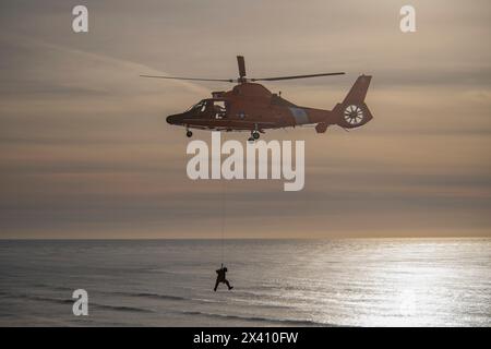 U. S. Coast Guard crew suspended below a Eurocopter MH-65 performing rescue training exercises at Cape Disappointment State Park near the mouth of ... Stock Photo