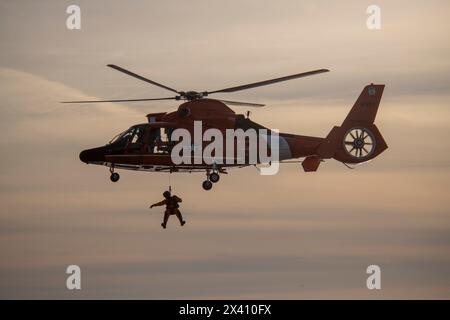 U. S. Coast Guard crew suspended below a Eurocopter MH-65 performing rescue training exercises at Cape Disappointment State Park near the mouth of ... Stock Photo