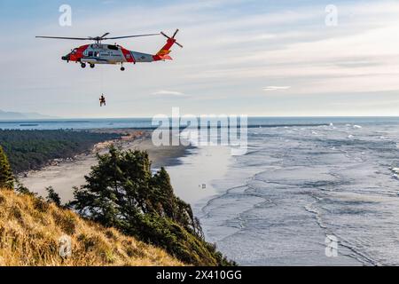 U. S. Coast Guard crew suspended below a Sikorsky MH-60J Jayhawk Performing rescue training exercises at Cape Disappointment State Park near the mo... Stock Photo