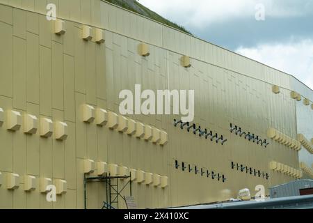 A large building with many windows and vents. The building is yellow and has a lot of windows. Stock Photo