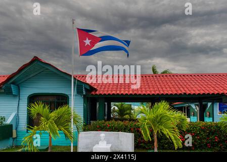 National flag of Cuba flying outside a turquoise building; Cayo Guillermo, Cuba Stock Photo