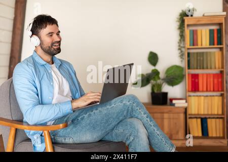 Man Sitting on Chair Using Laptop Computer And Headphones Stock Photo