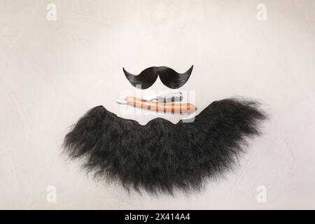 Artificial moustache, beard and straight razor on light background, flat lay Stock Photo