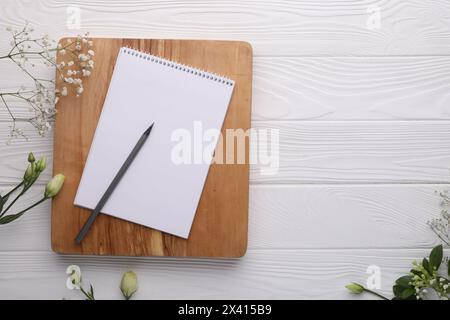 Guest list. Notebook, pencil and beautiful flowers on white wooden background, flat lay. Space for text Stock Photo