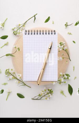 Guest list. Notebook, pen and beautiful spring tree blossoms on white background, flat lay Stock Photo