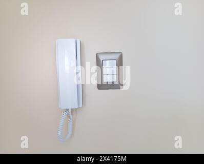 Simple intercom on white wall near the electric swithc. Stock Photo
