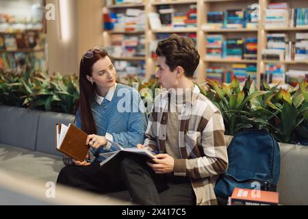 Young couple engaging in a thoughtful conversation in a bookshop Stock Photo