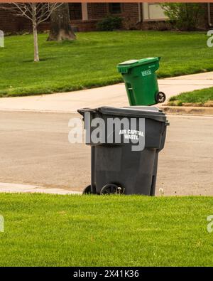Wheelie bins or trash recepticals at the curb of an urban street waiting for collection. Wichita, Kansas, USA. Stock Photo