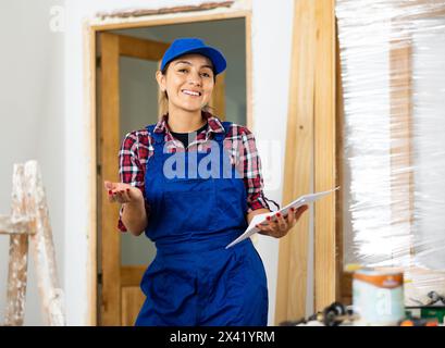 Positive woman builder with documents in apartment Stock Photo